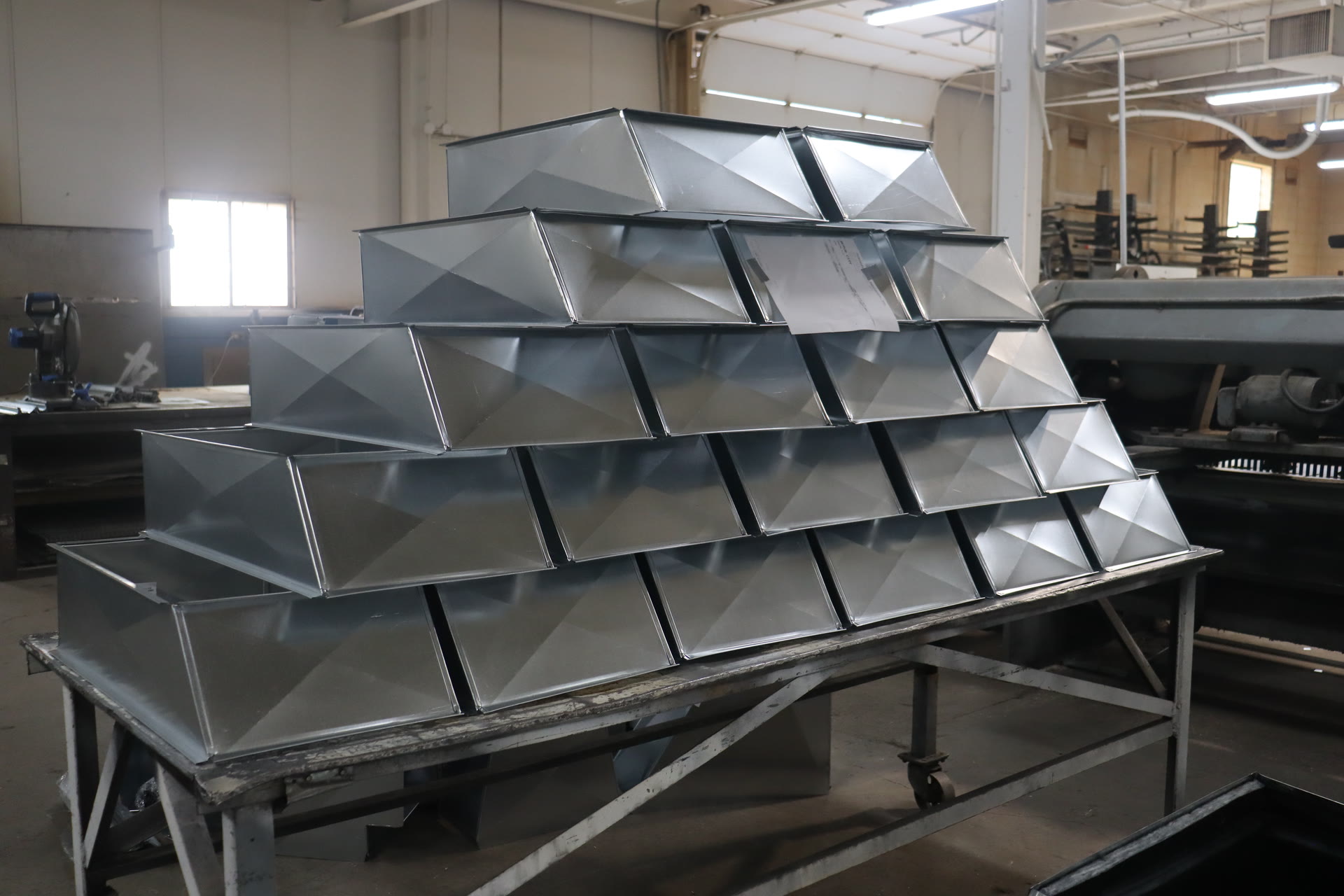 Freshly formed galvanized transitions stacked on a shop cart